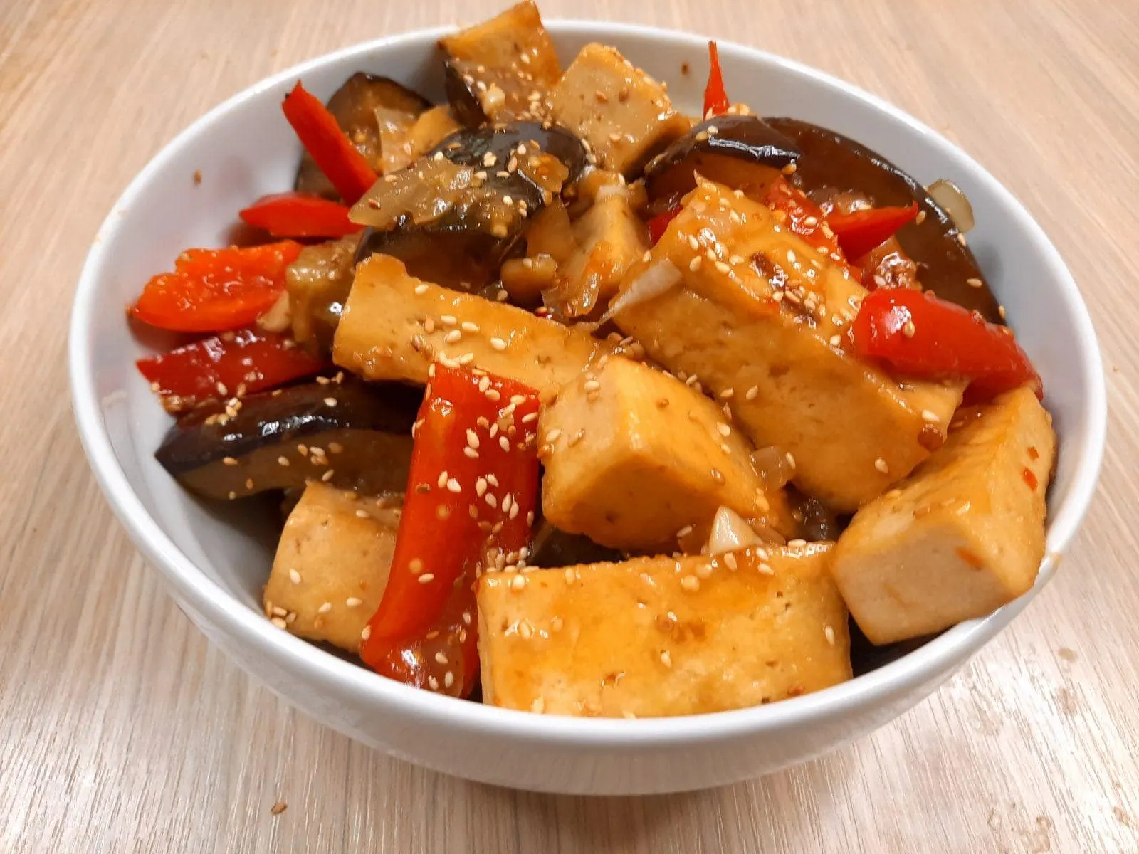 Cubes of fried tofu, eggplant and red capsicum in a dark glossy ginger and garlic sauce