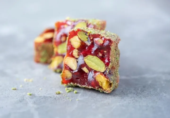 A slab of red Turkish delight studded with whole pistachios, cut to show the cross section