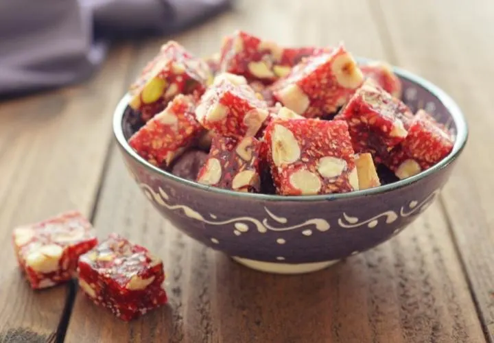 Red Turkish delight pieces with whole almonds set through them, served in a patterned bowl