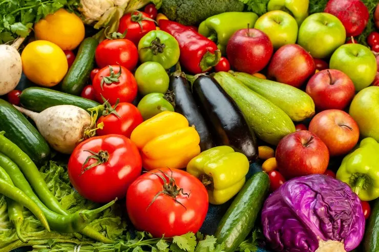 A vibrant assortment of fresh vegetables and fruits stacked together, symbolizing the benefits of a vegan diet for gut health.