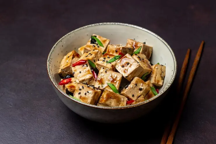  A bowl of crispy sweet chili tofu drizzled with sesame oil, perfect for a romantic Valentine's Day meal.